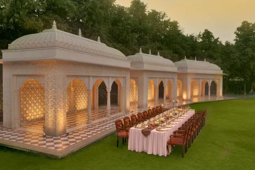 une longue table dans un kiosque avec des tables et des chaises dans l'établissement Heritage Village Resort & Spa Manesar-Gurgaon, à Gurgaon