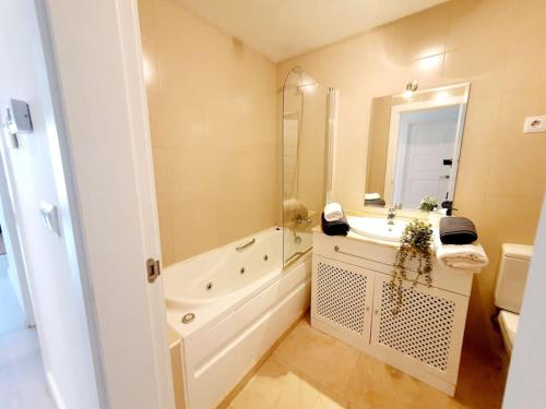 ein Badezimmer mit einer Badewanne, einem Waschbecken und einem Spiegel in der Unterkunft Ptabaja. a pie de piscina en el Valle Golf Resort in Murcia