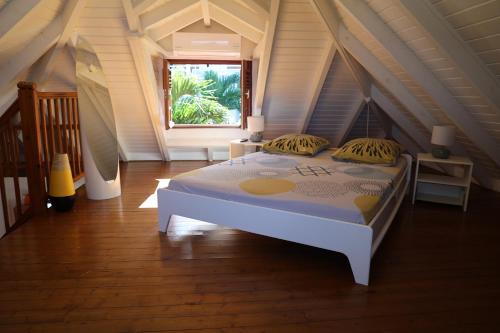 a bedroom with a white bed in a attic at Les bungalows du château d'Ô in Deshaies
