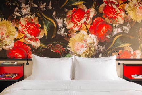 a bedroom with a painting of flowers on the wall at Leonardo Hotel Den Haag Babylon in The Hague