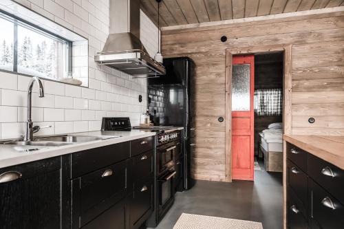 a kitchen with black cabinets and a red door at Luxurious cottage with sauna overlooking mountains in Vemdalsskalet