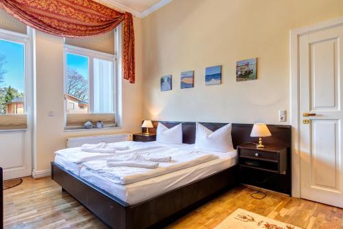 - une chambre avec un grand lit et 2 fenêtres dans l'établissement Villa Sonnenschein App. 8, à Heringsdorf