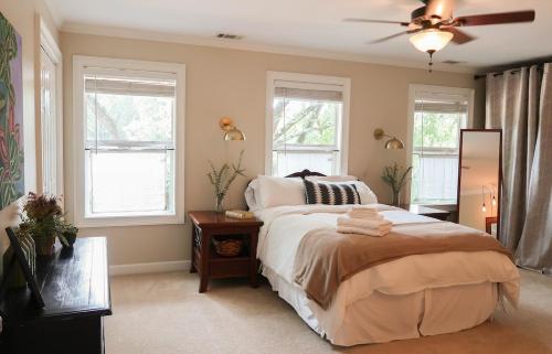 a bedroom with a bed with a ceiling fan and windows at Cozy Artist's Cottage-3br, Dt, Uga, Classic Cent in Athens