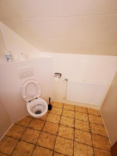 a bathroom with a toilet and a tiled floor at Landhaus Herdt in Lauda-Königshofen