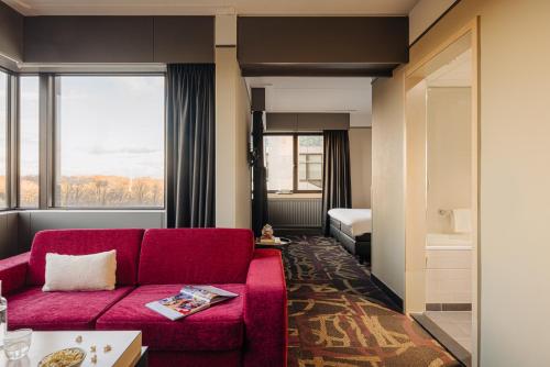 a living room with a red couch and a bedroom at Babylon Hotel Den Haag in The Hague