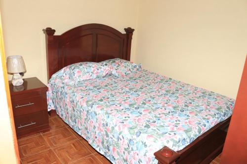 a bedroom with a bed with a floral bedspread and a night stand at Ramos Aparttment in São Filipe