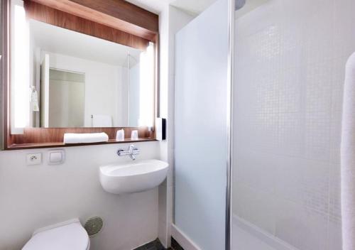 a bathroom with a toilet and a sink and a mirror at Campanile Lille - Seclin in Seclin