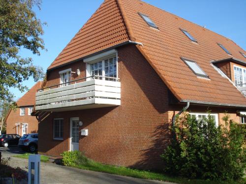 ein braunes Backsteinhaus mit einem weißen Balkon in der Unterkunft Sternschnuppe in Sankt Peter-Ording