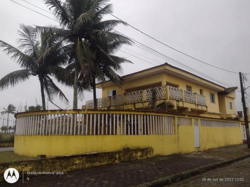 uma casa amarela com uma varanda e uma palmeira em Pousada em Mongaguà Kali 2 em Mongaguá