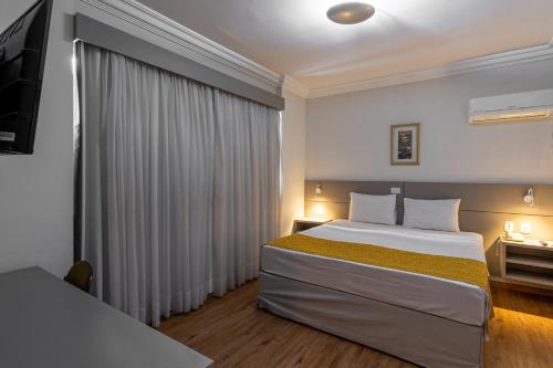 a hotel room with a bed and a television at Carlton Plaza São José dos Campos in São José dos Campos