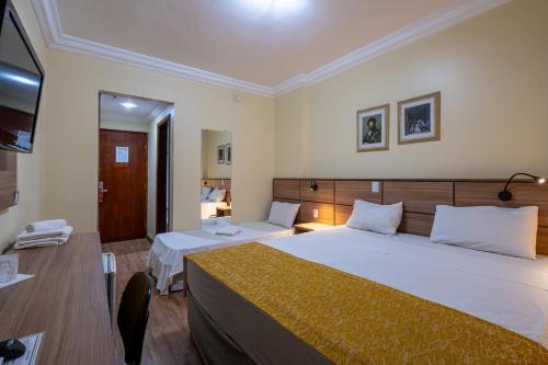 a hotel room with two beds and a television at Carlton Plaza São José dos Campos in São José dos Campos