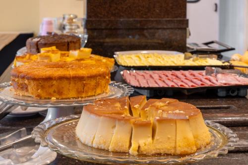a table with several different types of cakes on plates at Carlton Plaza São José dos Campos in São José dos Campos