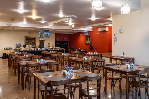 a restaurant with wooden tables and chairs and a bar at Carlton Plaza São José dos Campos in São José dos Campos