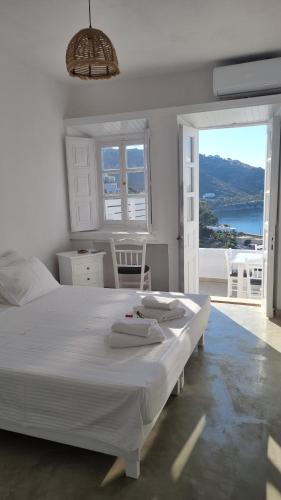 een witte slaapkamer met een groot bed met handdoeken erop bij Eirini Residences in Sapsila