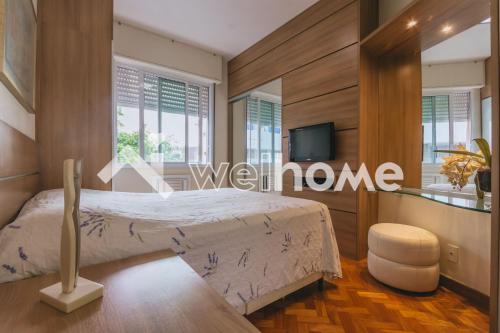 a bedroom with a bed and a tv and windows at Charmoso apartamento a 550m da Praia do Flamengo in Rio de Janeiro