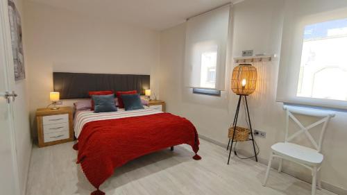 1 dormitorio con 1 cama con manta roja y lámpara en APARTAMENTO LA UNIÓN, en Castellón de la Plana