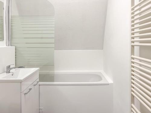 La salle de bains blanche est pourvue d'une baignoire et d'un lavabo. dans l'établissement T&K Apartments - 2 and 3 Room Apartments - Heart of Solingen-Hofgarten, à Solingen