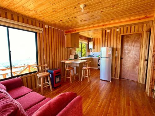 a living room with a couch and a kitchen with a refrigerator at Cabañas Vista al Mar in Valdivia