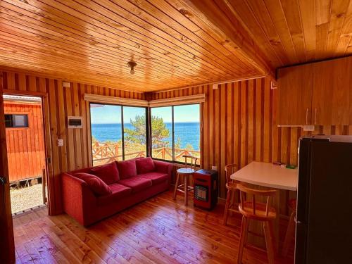 sala de estar con sofá rojo y mesa en Cabañas Vista al Mar en Valdivia