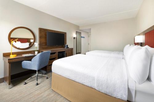 um quarto de hotel com uma cama, uma secretária e um espelho em Hampton Inn Long Island/Islandia em Islandia