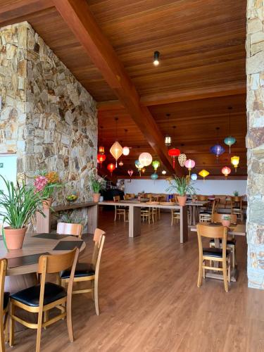a restaurant with tables and chairs and a stone wall at Wanderlust Experience Hotel BW Signature - Campos do Jordão in Campos do Jordão
