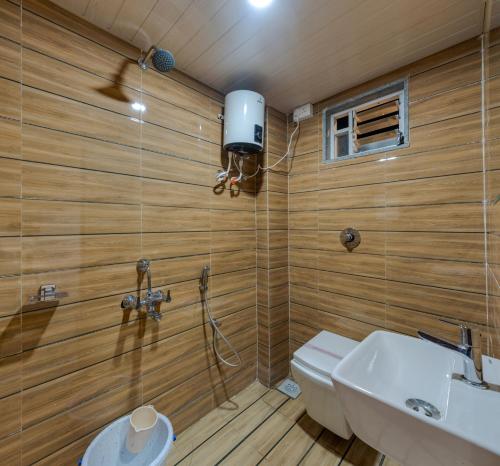 a bathroom with wooden walls and a toilet and a sink at Hotel Vimleshwar in Kolhapur
