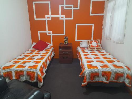 2 camas en una habitación con paredes de color naranja en Hospedajes Mary en Ushuaia