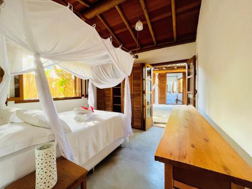 una camera con letto a baldacchino e tavolo in legno di Casa com piscina e vista para a Praia do Espelho a Porto Seguro