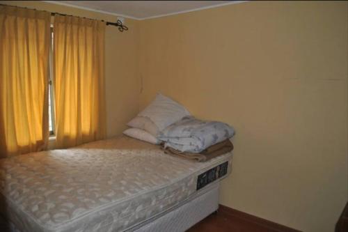 ein kleines Bett in einem Zimmer mit Fenster in der Unterkunft Casa Pichidangui, 8 personas. in Quilimarí