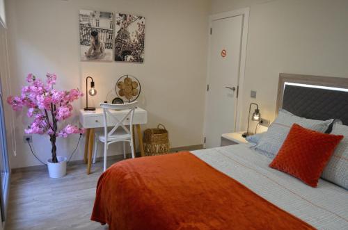 a bedroom with a bed with an orange blanket and a desk at Apartamento la Unión II , calidad y comodidad in Castellón de la Plana