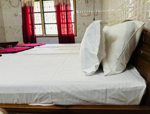 a bed with white sheets and pillows at shree katyayani residency in Gokarna