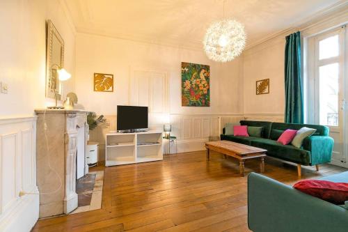 - un salon avec un canapé vert et une télévision dans l'établissement L'écrin des Ducs, à Dijon