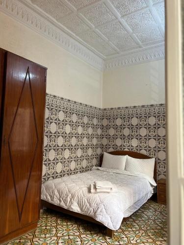 1 dormitorio con 1 cama en una habitación con pared en Riad Blue Garden en Rabat