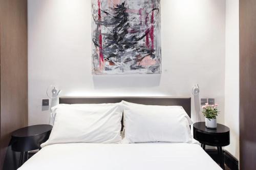 een slaapkamer met een wit bed en 2 zwarte tafels bij The One Bramham in Londen