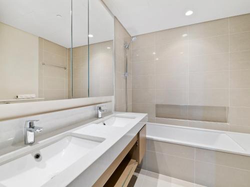 a white bathroom with two sinks and a bath tub at Mesmerizing 2BDR in Creek Harbour HG1-1907 in Dubai