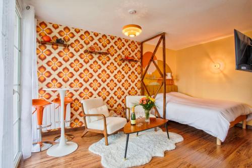 a bedroom with a bed and a chair and a table at Suite année 70 - Jacuzzi et Balcon in Caen