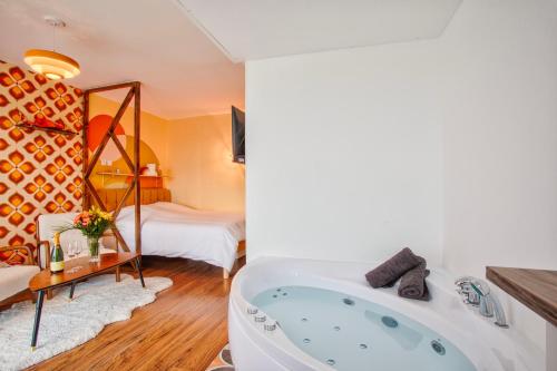 a bathroom with a tub and a bedroom at Suite année 70 - Jacuzzi et Balcon in Caen