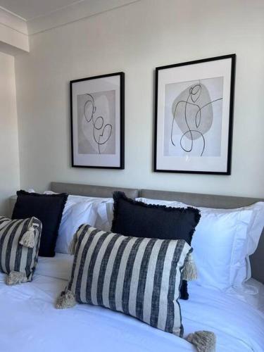 a white bed with pillows and two pictures on the wall at Guest Homes - Driffield Apartment in Great Driffield