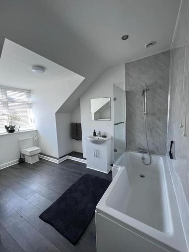 a large white bathroom with a tub and a sink at Guest Homes - Driffield Apartment in Great Driffield