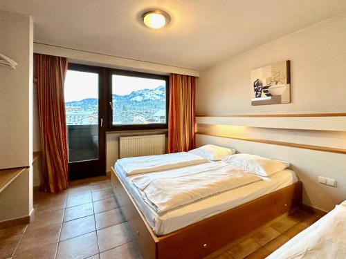 - une chambre avec un lit et une grande fenêtre dans l'établissement Apartments Max & Moritz, à Kirchberg in Tirol