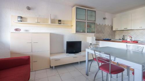 une cuisine avec une table et des chaises ainsi qu'une télévision dans l'établissement Welcomely - Acqua e Tramonto, à Olbia