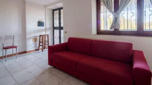 - un canapé rouge dans le salon doté d'une fenêtre dans l'établissement Welcomely - Acqua e Tramonto, à Olbia