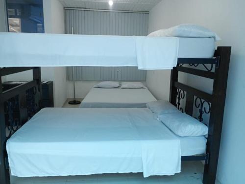 two bunk beds in a room with white sheets at Apartamento de verano en la Represa del Prado 2 de 2 in Boquerón de Tena