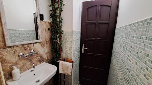 a bathroom with a sink and a black door at Kisdiófa Panzió és Vendéglő in Vajdácska