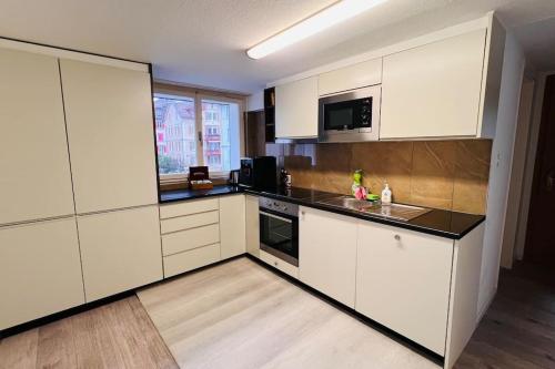 a kitchen with white cabinets and a black counter top at Cresta Apartment in St. Gallen