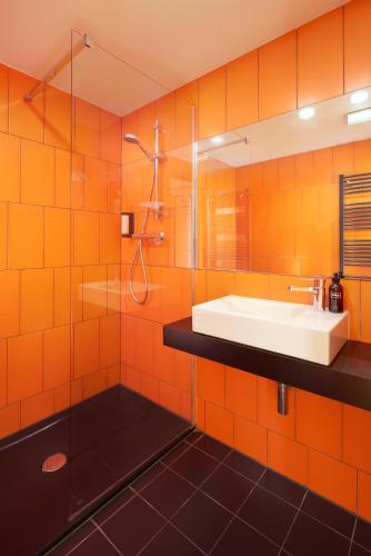 an orange tiled bathroom with a sink and a shower at MeetMe23 in Prague