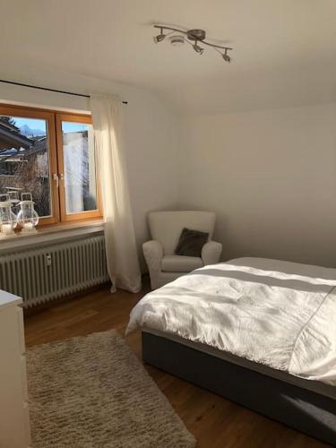 a bedroom with a bed and a chair and a window at Alpsoul eine Ferienwohnung mit Charisma…. in Garmisch-Partenkirchen