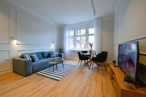 Porta Apartments Novi Sad في نوفي ساد: غرفة معيشة مع أريكة زرقاء وطاولة