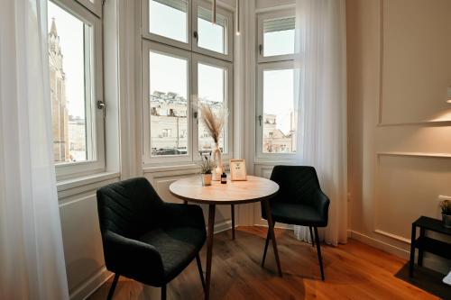 una mesa y 2 sillas en una habitación con ventanas en Porta Apartments Novi Sad en Novi Sad
