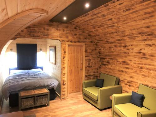 a bedroom with a bed and two chairs in it at Kendoon Cabin in Carsphairn